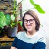 Photograph of illustrator Alba Celdran, who is in front of a houseplant.