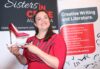 Romany Rzechowicz holds the scarlet stiletto trophy in front of a Sisters in Crime backdrop