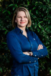 Photograph of Riikka Dunn in front of green leaves